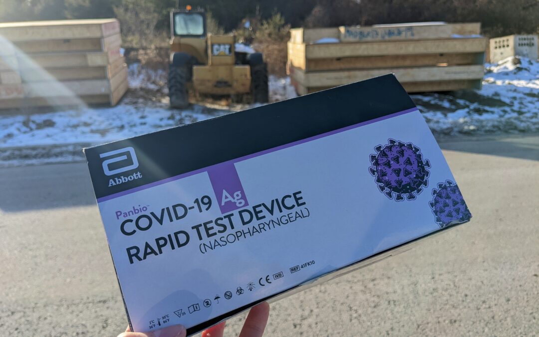 A box of rapid tests held in front of a construction site