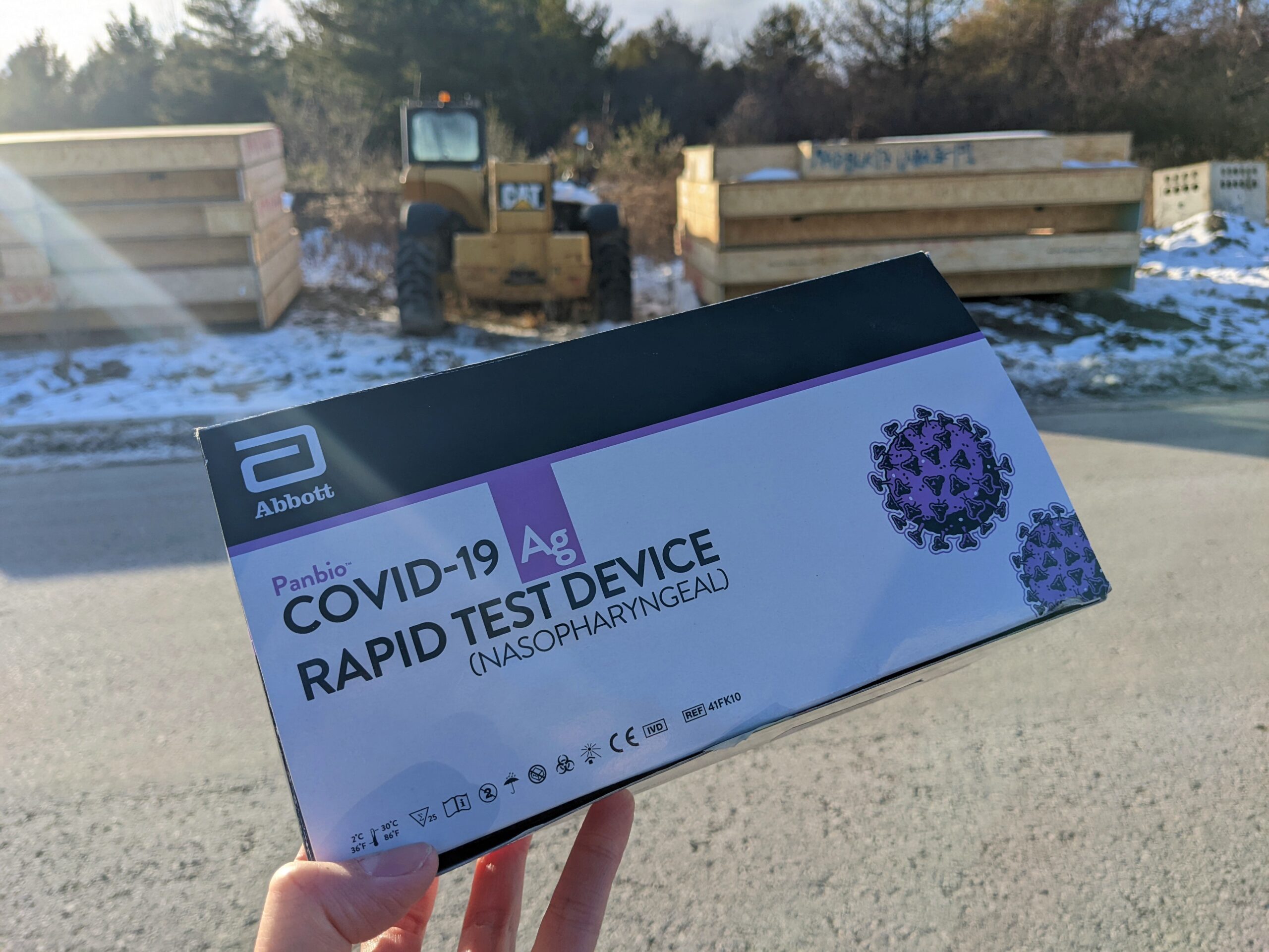 A box of rapid tests held in front of a construction site